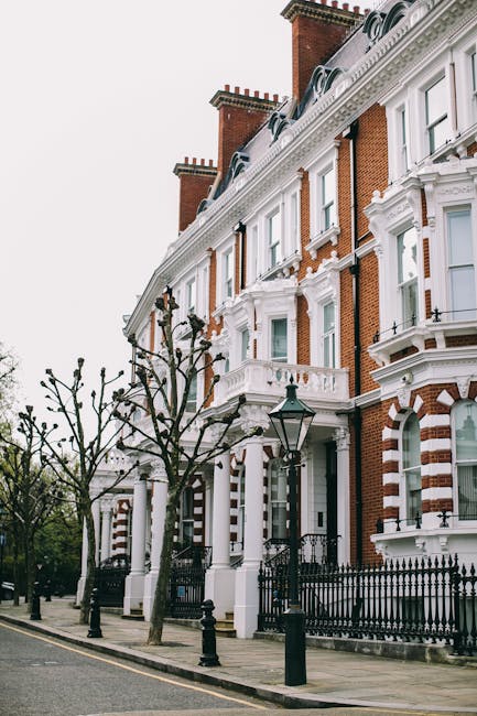 Exterior view of a historic multi-story building in West Putney Estates, featuring cream-colored facades with decorative moldings and large rectangular windows framed by white trim. The building has o